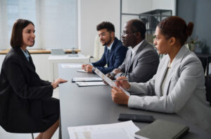 An applicant answering job interview questions in the front or three recruiters.